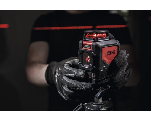 Person hält einen JC Schwarz Kreuzlinienlaser auf einem Stativ