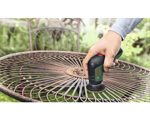 Drahtbürste im Einsatz an einem Gartentisch aus Metall