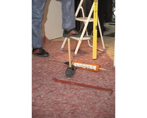 Szene mit Werkzeugen wie Hammer, Leiter, Wasserwaage und Dichtstoffpistole auf einer Schutzmatte.