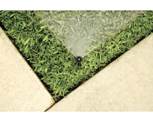 Bewässerungssystem auf Rasenfläche in der Nähe von Betonplatten