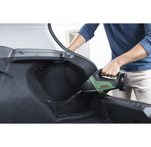Une personne aspire le coffre d''une voiture avec un aspirateur à main sans fil. Logo Bosch.