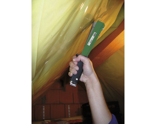 Eine Person befestigt mit einem Tacker Folie an einer Dachkonstruktion.