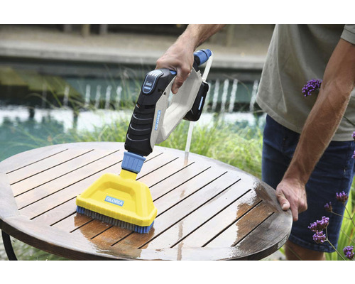 Akkubürste zur Reinigung eines Holztisches im Außenbereich