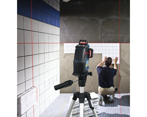 Carreleur utilisant un laser lignes croisées pour aligner les carreaux sur le mur.