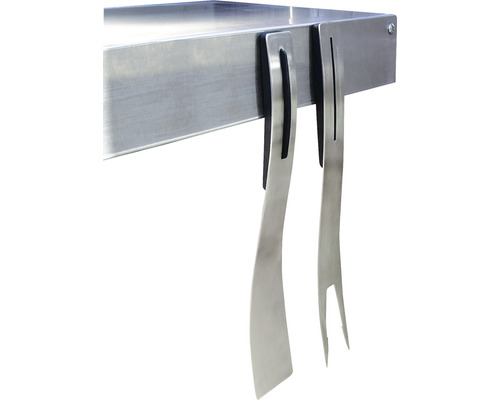 Des accessoires de barbecue tels qu''une spatule et une fourchette en métal sont suspendus à une table de barbecue.