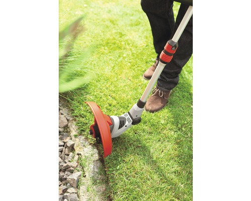Une personne utilise un coupe-bordure pour l''entretien de la pelouse dans le jardin.