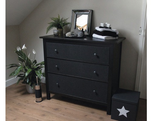 Chambre à coucher avec commode noire à trois tiroirs, miroir et plantes d''intérieur