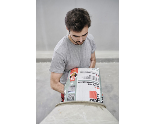 Mann schüttet Garten- und Landschaftsbaubeton in einen Betonmischer.