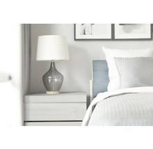 Nachttischlampe auf einem Nachttisch neben einem Bett in einem Schlafzimmer.