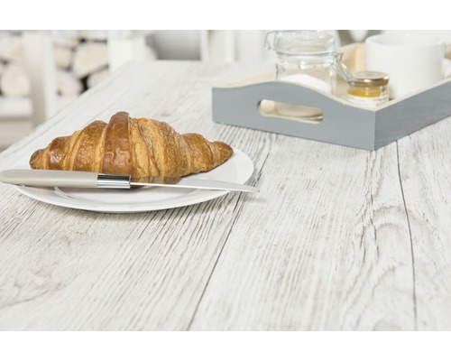 Un croissant avec un couteau sur une assiette et un plateau de petit-déjeuner sur une table en bois.