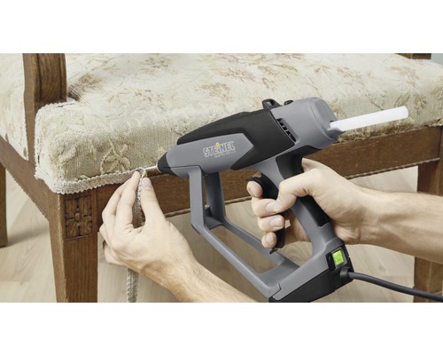 Heissklebepistole beim Anbringen einer Zierleiste an einem Stuhl