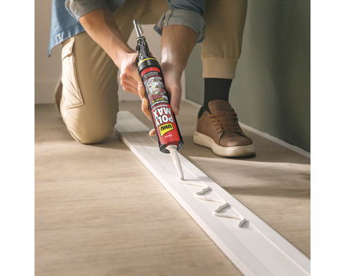 Une personne applique de la colle sur une plinthe à l''aide d''un pistolet à colle.