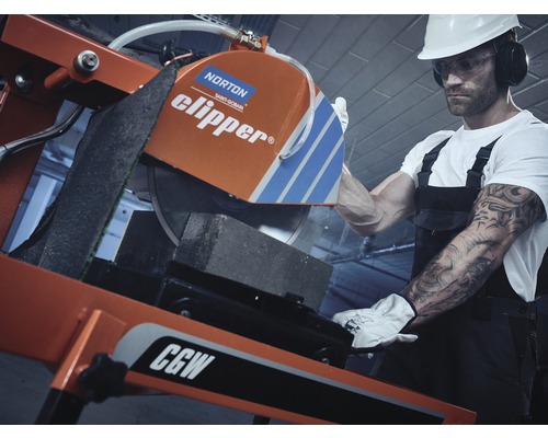 Un ouvrier du bâtiment coupe une pierre avec une scie à pierre.