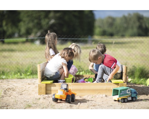 Kinder spielen in einem Sandkasten aus Holz mit Spielzeug im Freien