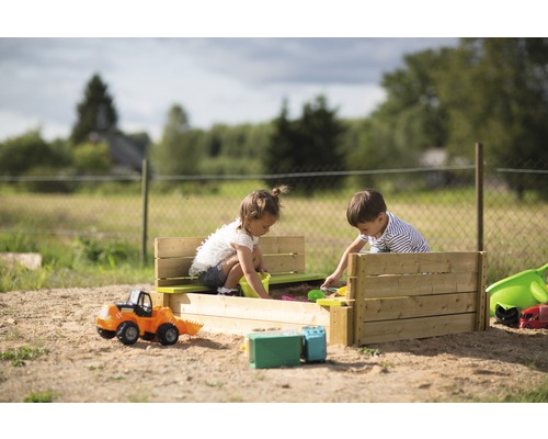 Zwei Kinder spielen in einem Sandkasten mit Sitzbank und Spielzeug