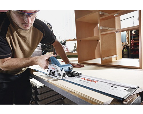 Un homme scie du bois avec une scie plongeante Bosch et un rail de guidage.