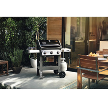 Barbecue Weber sur une terrasse avec une table à manger et un jardin en arrière-plan