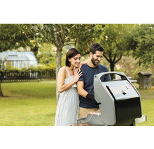 Un couple fait un barbecue dans un jardin avec un gril à gaz