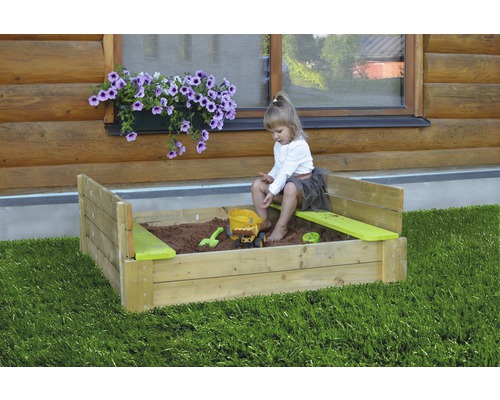 Kind spielt in Sandkasten mit Spielzeug im Garten