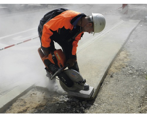 Ouvrier du bâtiment coupant de la pierre avec une scie à pierre sur un chantier.
