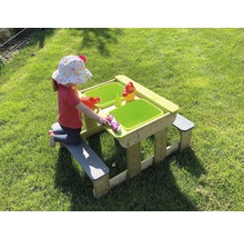 Enfant jouant à une table de sable et d''eau avec des bancs dans le jardin.