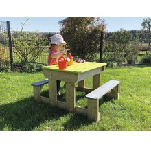 Un enfant joue à une table de pique-nique dans le jardin. La table en bois a des bancs et un plateau vert.