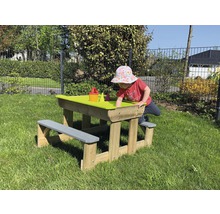 Enfant jouant à une table à sable avec banc en bois dans le jardin