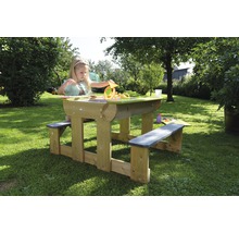 Enfant jouant à une table de pique-nique en bois avec fonction de bac à sable dans le jardin.