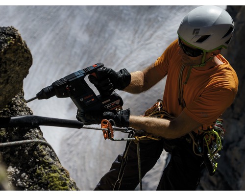Ein Mann bohrt mit einem Akku Bohrhammer von Bosch in einen Felsen.