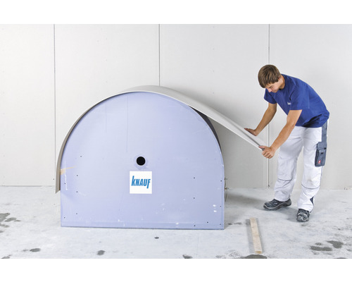 Un homme plie une plaque de plâtre autour d''un élément préfabriqué de Knauf