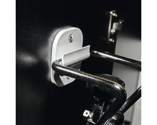 Detailaufnahme eines schwarzen Möbelstücks mit verchromtem Griff und weißer Halterung