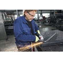 Mann schleift Metall mit einem Winkelschleifer in einer Werkstatt