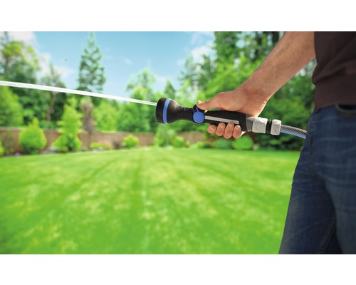 Eine Person bewässert einen Garten mit einer Gartenspritze.