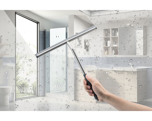 Main avec raclette à vitre devant des carreaux de salle de bain