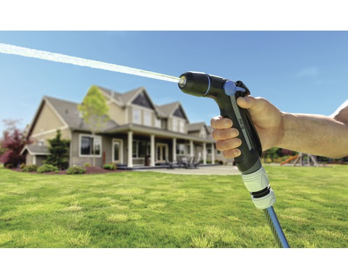 Gartenspritzpistole mit Wasserstrahl und Haus im Hintergrund