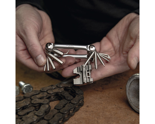 Multitool dans les mains avec chaîne de vélo sur la table