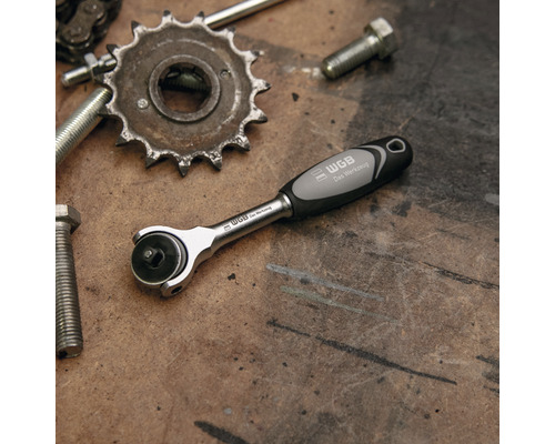 Clé à cliquet WGB à côté de vis et d''une roue dentée sur un établi