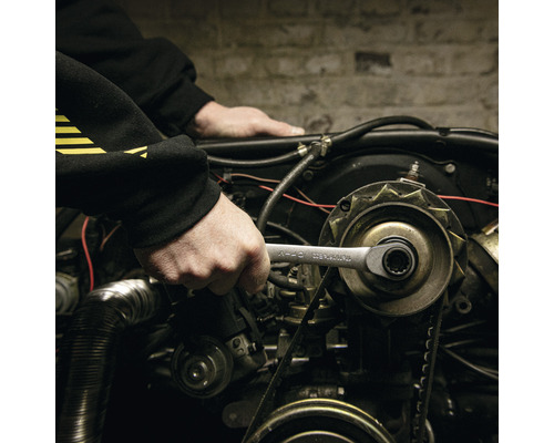 Une personne utilise une clé sur un moteur.