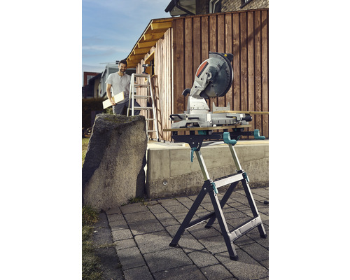 Scie à onglet sur table de sciage à l''extérieur avec une personne sur une échelle