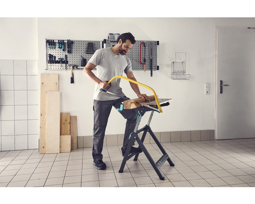 Homme sciant du bois sur un établi avec une scie à métaux.