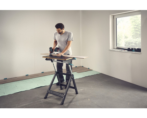 Un homme coupe du stratifié sur un établi avec une scie circulaire.