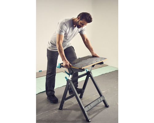 Un homme travaille sur un établi. L''établi a une surface de travail avec des trous et un cadre en forme de A.