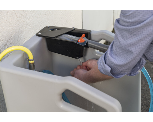 Lavabo extérieur avec robinet et mains en train de se laver