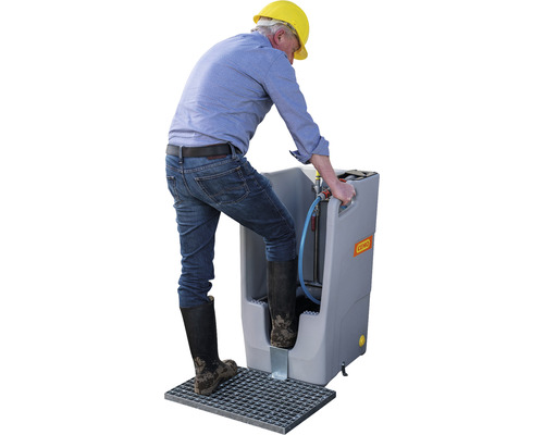 Une personne utilise une installation de lavage de chaussures pour nettoyer ses bottes.