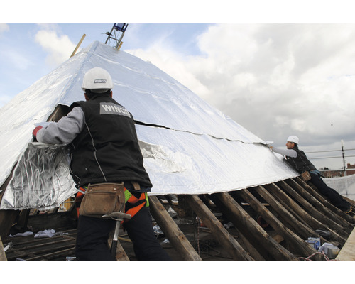 Deux ouvriers du bâtiment installent une isolation de toit sur un toit.