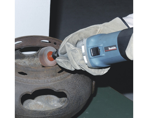 Une personne utilise une meuleuse droite de la marque Makita pour nettoyer un objet métallique.