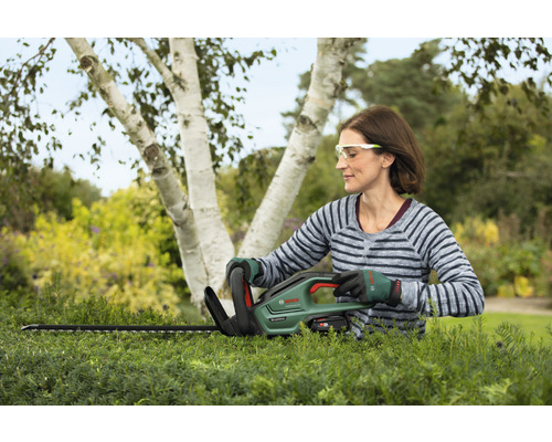 Frau schneidet Hecke mit Akku-Heckenschere von Bosch