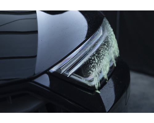 Gros plan d''un phare de voiture avec de la mousse de nettoyage