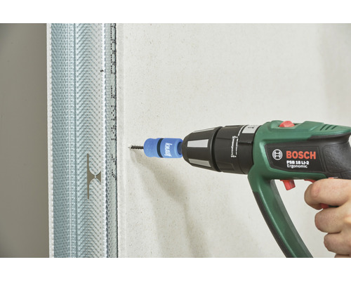Un homme utilise une visseuse sans fil Bosch pour visser une vis dans une plaque de plâtre. Le mur est soutenu par un profilé métallique.