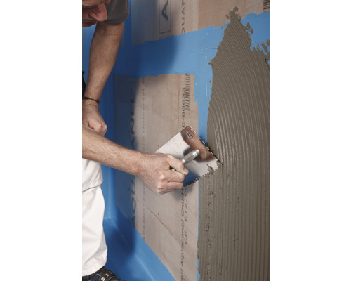 Handwerker trägt Kleber auf eine Aquapanel-Platte auf